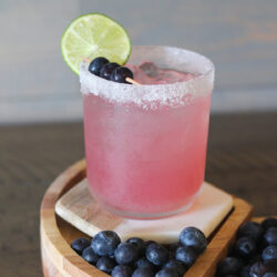 Blueberry margarita in a glass with a salted rim.