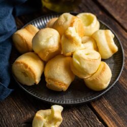 Brazilian cheese bread stacked on a black serving platter.