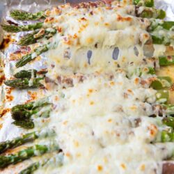 Cheesy baked asparagus on a baking sheet.