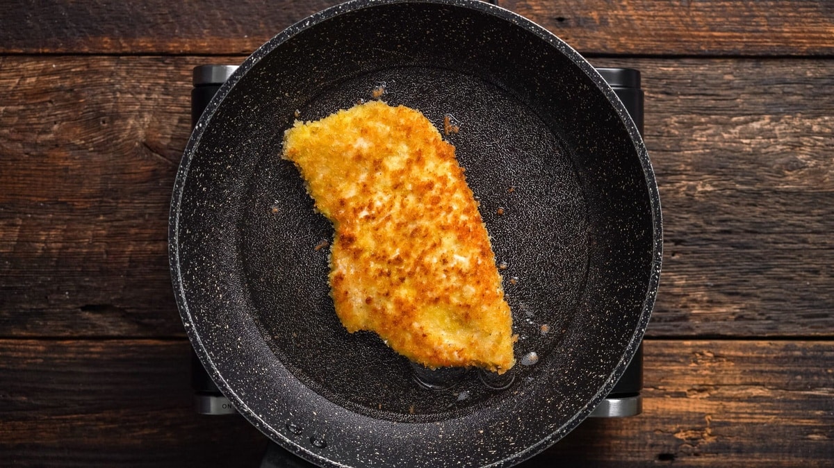 Chicken Paillard cooking in a non-stick frying pan.