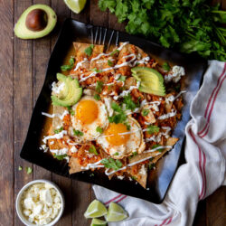 Chilaquiles chips and sauce served on a black plate.