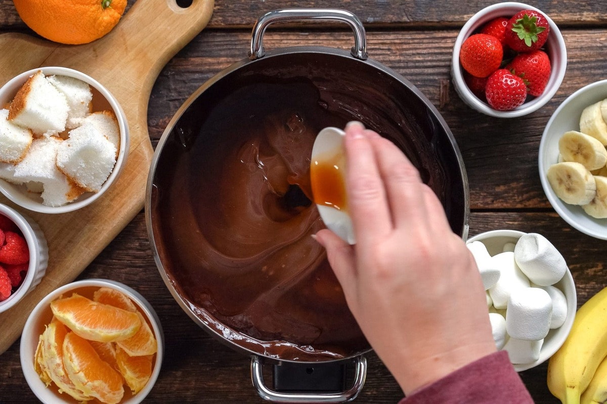 Pouring vanilla on the electric pot with the chocolate.