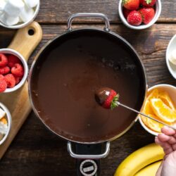 Strawberry dipped in a milk chocolate fondue pot.