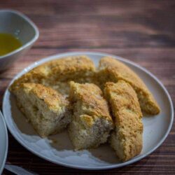 Rosemary focaccia on a white plate with a side of olive oil for dipping.