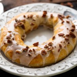 A slice of Danish Kringle served on a plate, topped with icing.