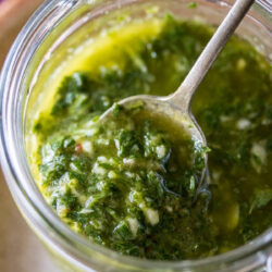 A close-up of chimichurri sauce in a glass jar.