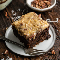 This German Chocolate Poke Cake recipe is a rich and indulgent dessert featuring a moist chocolate cake topped with a smooth chocolate ganache and coconut pecan frosting.