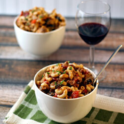 Two servings of German goulash and a glass of wine on a table.