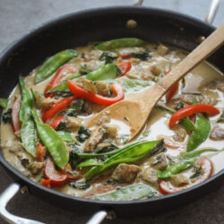 Green curry sauce simmering in a black skillet.