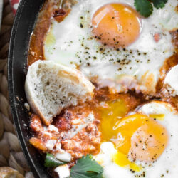 North African shakshuka in a skillet, served with crusty bread.