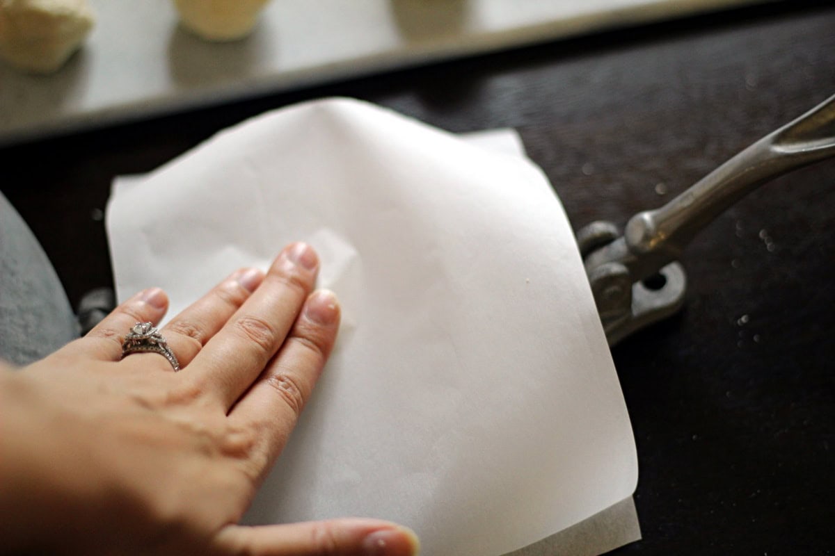 Setting the second piece of parchment paper on top of the dough.