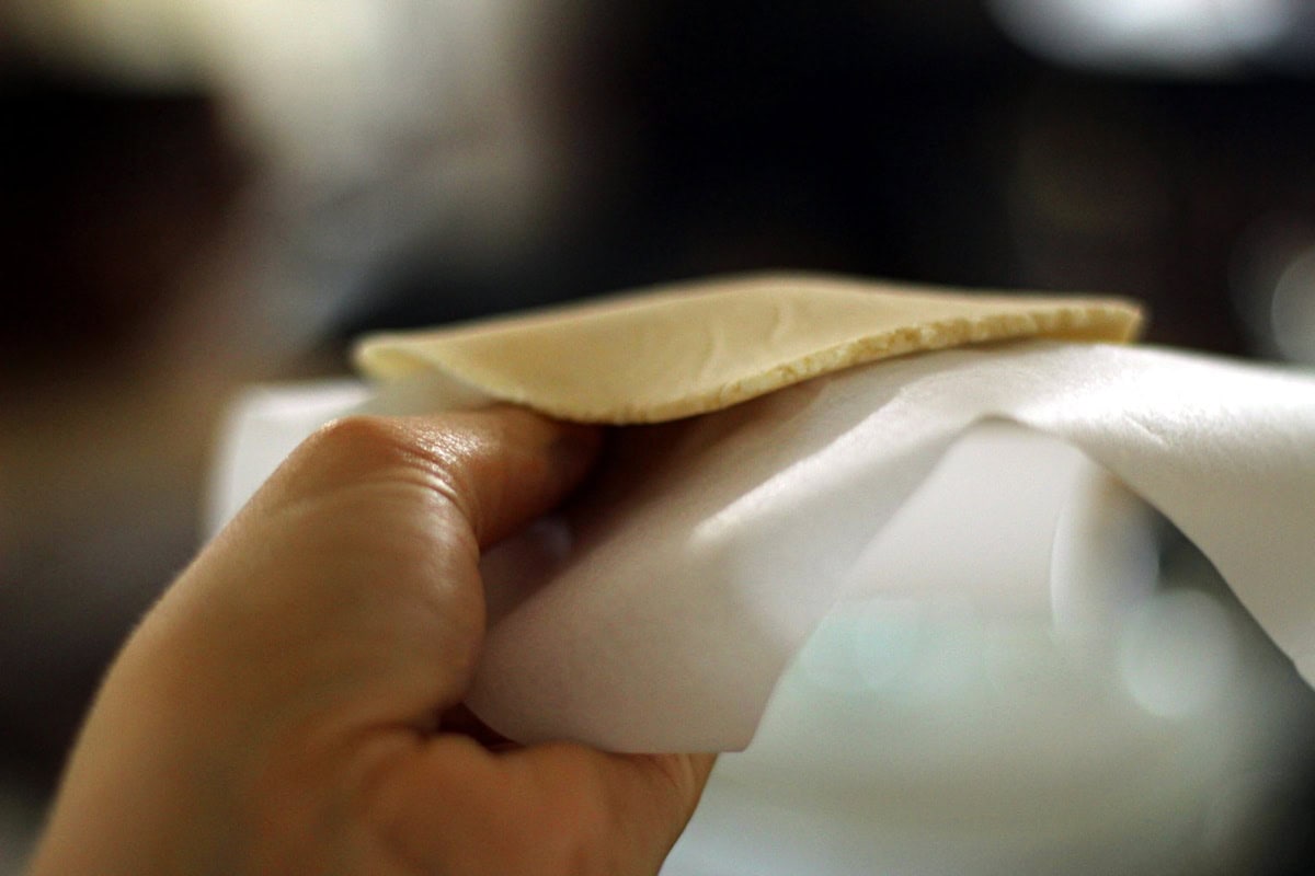 Peeling the paper away from the tortilla.