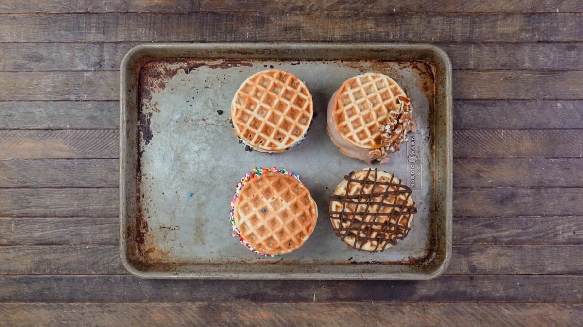 Homemade waffle ice cream sandwiches on a well-used baking tray.