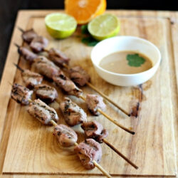 Indonesian Pork Satay skewers arranged on a wooden board.