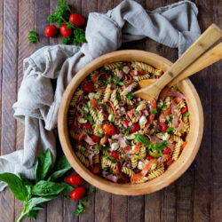 Italian pasta salad with pepperoni in a large wooden bowl.