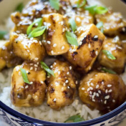 Lemon Chicken with soy sauce, garnished with sesame seeds and green onions over rice.