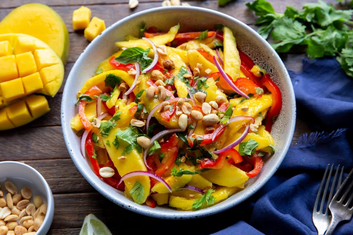 Mango salad in a bowl, garnished with roasted peanuts.