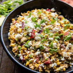Overhead view of one bowl and one black serving dish of Mexican corn salad.
