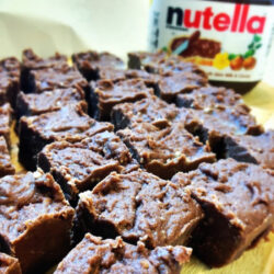 Nutella fudge with a jar of Nutella in the background.