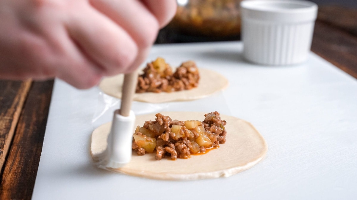Brushing the wrapper with water.