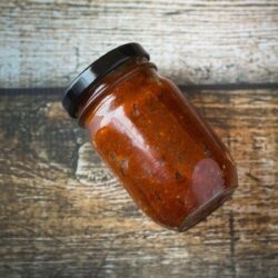 A jar of homemade red curry paste on a table.