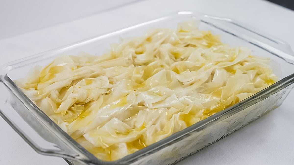 Brushing the top layer of crumpled phyllo dough with olive oil.