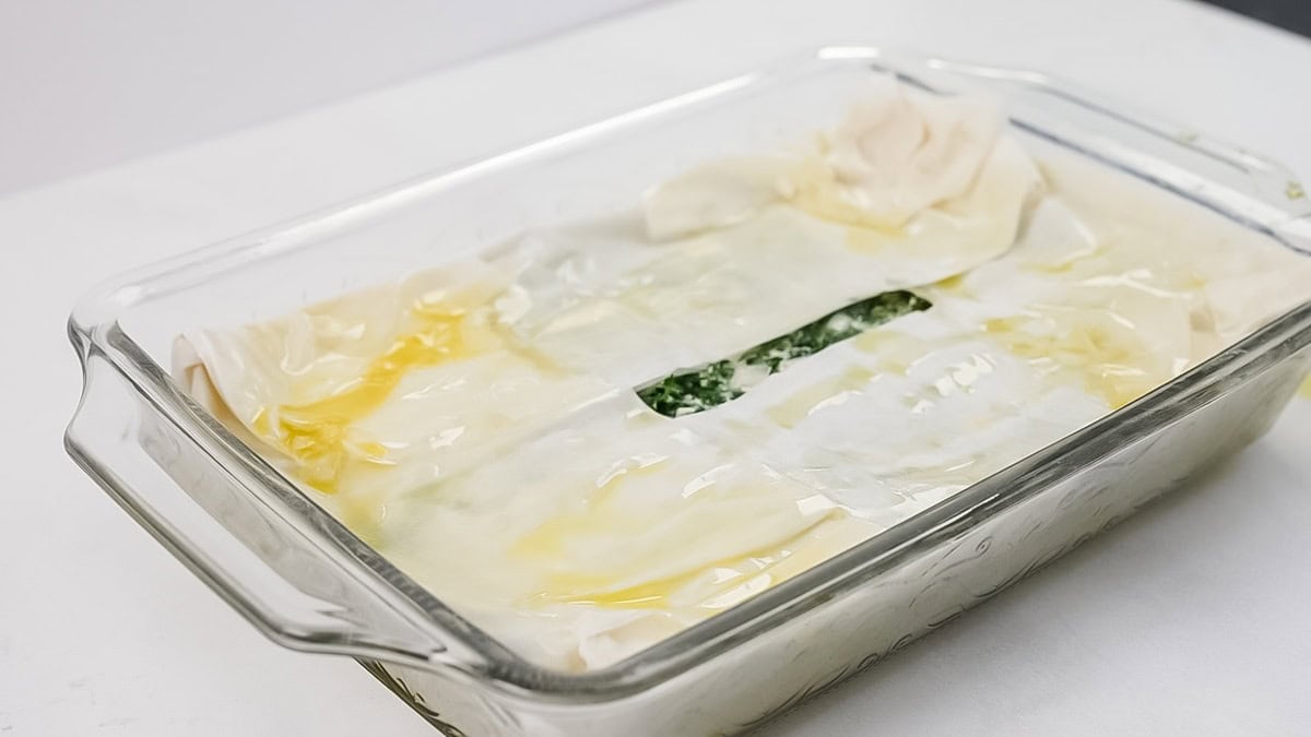 Brushing olive oil on the top of the phyllo dough.